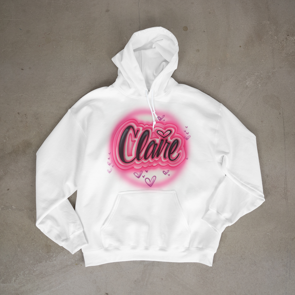 White hoodie with 'Claire' design on a gray surface