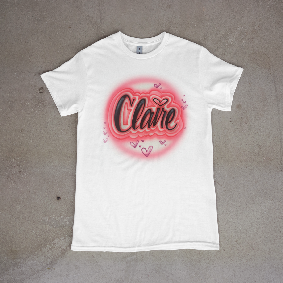 White t-shirt with 'Claire' design on a gray surface