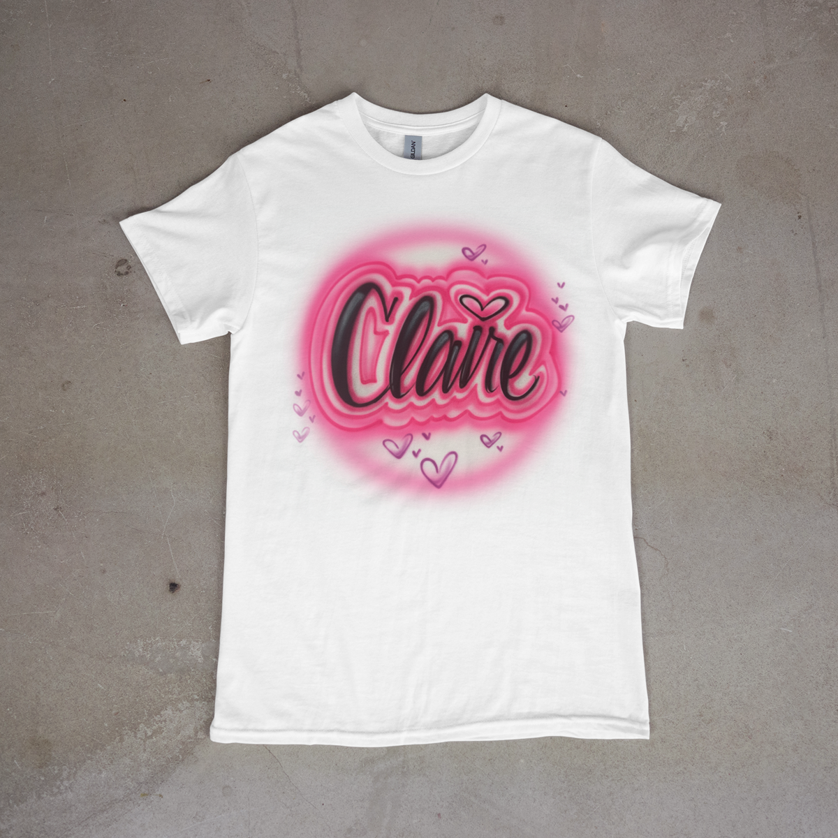 White t-shirt with pink and black design on a gray surface